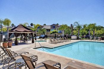 A pool area with chairs and a gazebo.