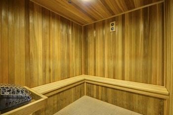 A wooden room with a bench and a basket on the floor.
