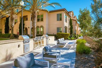 A patio with chairs and a grill in front of a building