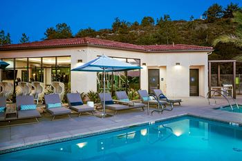 A resort style pool with lounge chairs and umbrellas