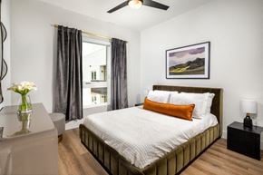 San Diego apartment for rent - A bedroom with a large bed, a ceiling fan, and a painting on the wall.