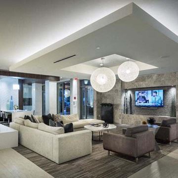 San Diego apartment for rent - A modern living room with a large sectional sofa and a flat-screen TV mounted on the wall.