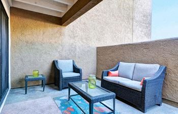 A patio with a sofa, chair, and table.