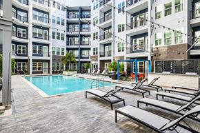 Tampa apartment for rent - an outdoor swimming pool with chaise lounge chairs in front of an apartment building
