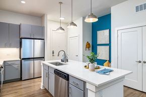 Tampa apartment for rent - a kitchen with a large white island with a stainless steel refrigerator and dishwasher
