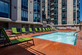 San Francisco apartment for rent - a swimming pool with green lounge chairs and a large building in the background