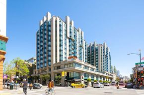 San Francisco apartment for rent - a man riding a bike down a street next to a tall building