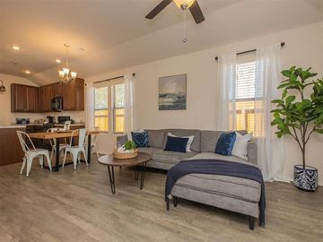 Conroe apartment for rent - A living room with a grey couch and a dining table with white chairs.