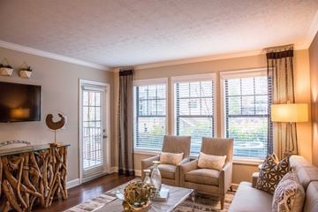 Atlanta apartment for rent - A living room with a white couch, a wooden table, and a television on the wall.