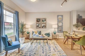 Herriman apartment for rent - A living room with a blue chair, a white couch, and a rug with blue and yellow flowers.