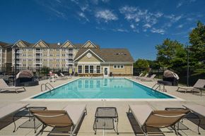 Elkridge apartment for rent - a swimming pool with chairs and a building in the background