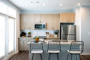 Raleigh apartment for rent - a kitchen with wooden cabinets and a counter with three chairs