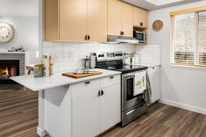 Kirkland apartment for rent - a kitchen with white cabinets and a stove and a fireplace at Scout, Kirkland, WA