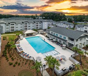 Ladson apartment for rent - an aerial view of an apartment complex with a swimming pool at sunset
