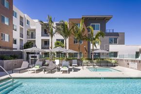 North Hollywood apartment for rent - a swimming pool with chairs and umbrellas in front of a building