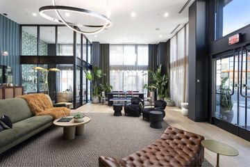 North Hollywood apartment for rent - A modern living room with a green couch and a brown leather ottoman.