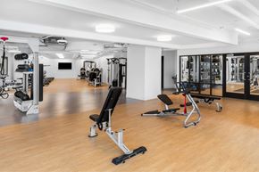 New Rochelle apartment for rent - a gym with weights and cardio equipment in a room with wood floors