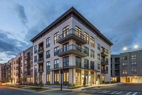 Charlotte apartment for rent - A modern apartment building with balconies and multiple windows is illuminated at dusk.
