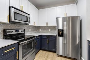 Charleston apartment for rent - Apartments in Charleston, SC, with In-Unit Washer and Dryer - The Avenues at Verdier Pointe - Kitchen with Wood-Style Flooring, Two-Tone Cabinetry, Range, French Door Refrigerator, and Mounted Microwave.