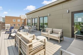 Beverly apartment for rent - A patio with wooden furniture and a building in the background.