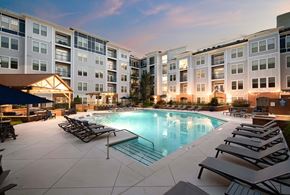 Brookhaven apartment for rent - A swimming pool surrounded by lounge chairs in front of apartment buildings.