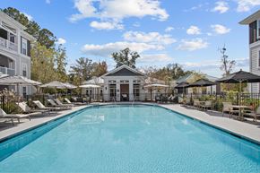 Charleston apartment for rent - a swimming pool with chairs and umbrellas in front of a building
