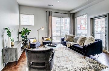 Denver apartment for rent - A living room with a black couch and a grey chair.