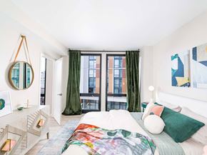Washington apartment for rent - A bedroom with a large bed and a window with green curtains.