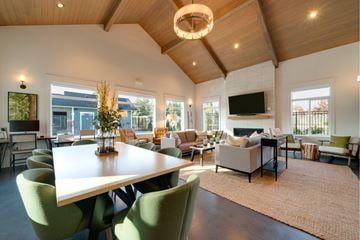 Lakewood apartment for rent - A modern living room with a large white table and green chairs.