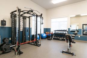 Lakewood apartment for rent - A gym with a variety of equipment including a squat rack, bench press, and a mirror.