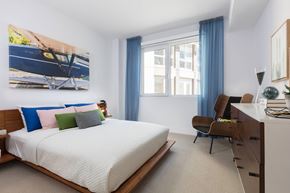 Foster City apartment for rent - A bedroom with a large bed and a painting of a boat on the wall.