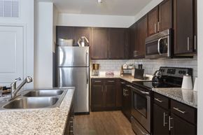 Frisco apartment for rent - A kitchen with dark wood cabinets and stainless steel appliances.