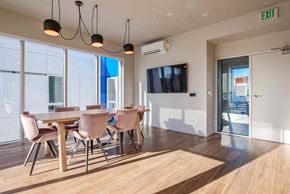 Seattle apartment for rent - A conference room with a long table and chairs, a television, and a view of the outside.