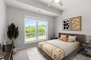 Cottage Grove apartment for rent - A bedroom with a large bed and a view of the outdoors through a large window.