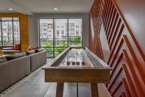 Lansing apartment for rent - A shiny pool table is in the middle of a room with a couch and a window.