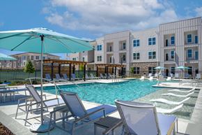 Gonzales apartment for rent - A pool area with chairs and umbrellas in front of a building.