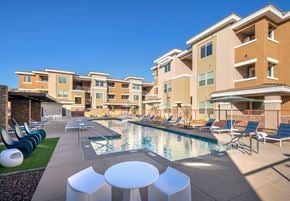 Chandler apartment for rent - A pool area with lounge chairs and tables in front of apartment buildings.