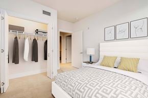 San Jose apartment for rent - A bedroom with a large bed and a closet with clothes hanging.