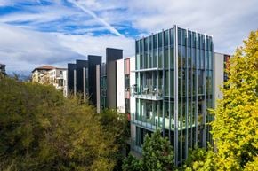 San Jose apartment for rent - A modern glass building is surrounded by trees.