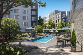 Salem apartment for rent - A pool surrounded by trees and chairs with a building in the background.