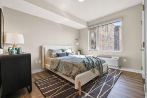 West New York apartment for rent - A bedroom with a large bed and a window overlooking a city.