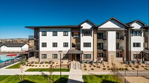 Colorado Springs apartment for rent - A large, modern building with a pool in the foreground.