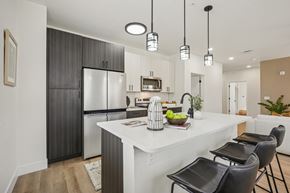 Colorado Springs apartment for rent - A modern kitchen with a white island and black chairs.