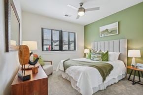 Colorado Springs apartment for rent - A bedroom with a large bed, a wooden side table, and a ceiling fan.