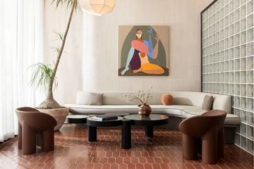 West Hollywood apartment for rent - A living room with a white sofa, a brown chair, a coffee table, and a painting on the wall.