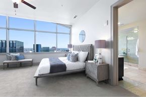 Austin apartment for rent - A bedroom with a large bed and a view of the city.