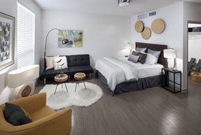 Denver apartment for rent - A modern bedroom with a large bed and a yellow armchair.