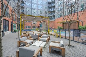 Raleigh apartment for rent - A patio with wooden furniture and a pool in the background.