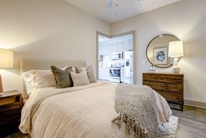 Raleigh apartment for rent - A bedroom with a large bed, a dresser, and a mirror.