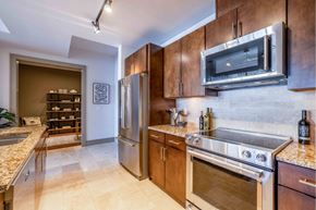 Seattle apartment for rent - A kitchen with a stainless steel refrigerator and oven, wooden cabinets, and a marble countertop.